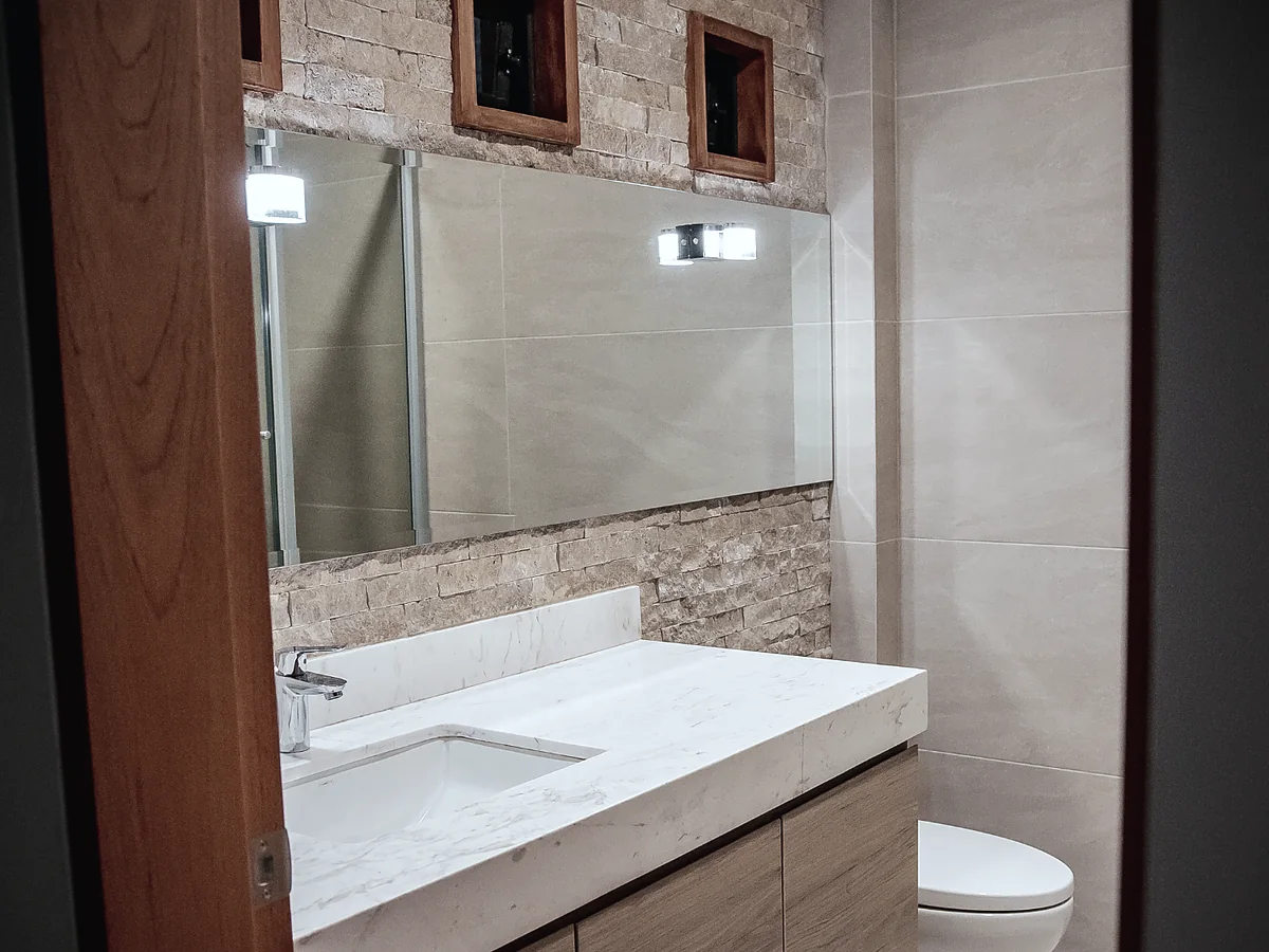 Baño remodelado con piedra decorativa y mueble de madera